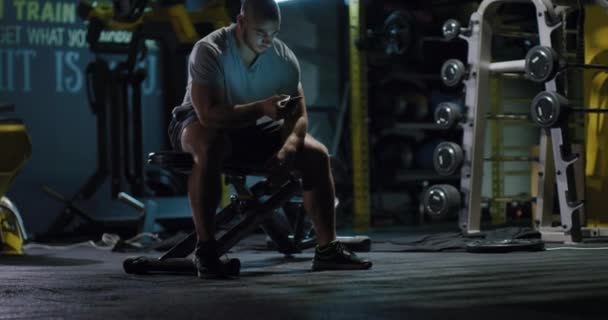 Muscular Crossfit Bodybuilder having a Break Checking Social Networks Fitness Equipment Tło Centrum fitness Fitness Trening Rest Fitness Technology Concept 4k — Wideo stockowe