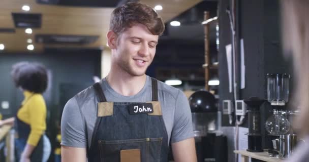 Smiling Man At Counter Handing Payment Terminal Il cliente utilizza un metodo di pagamento moderno Finanza futuristica Transazione senza contatto Red Epic 8k — Video Stock