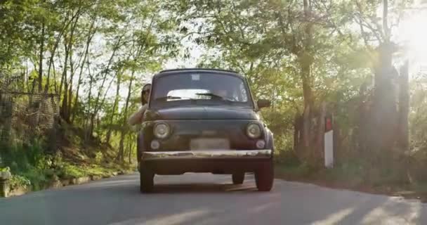 Hermosa pareja joven en luna de miel en viejo coche retro éxito soleado vacaciones acción cámara lenta tiro rojo épica 8k — Vídeos de Stock