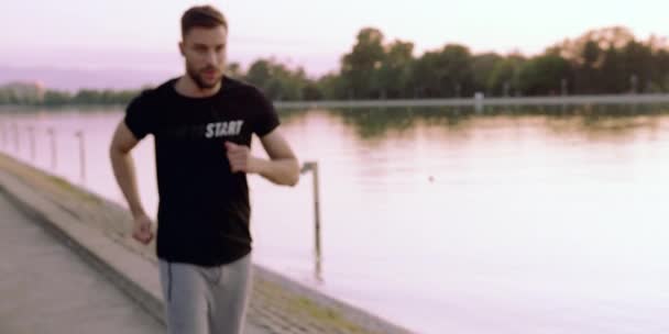 Fit mladý muž jogging poslech hudby s sluchátky při východu slunce aktivní životní styl západ slunce pomalý pohyb 8k červená Epic — Stock video