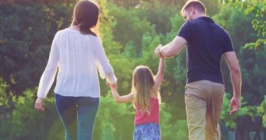 Mutlu ve çocuklu güzel bir aile Sunset Ailesi 'nin geleceğinde parkta yürüyor. Evlilik mutluluğu. Kırmızı destansı 8K' da yavaş çekim.