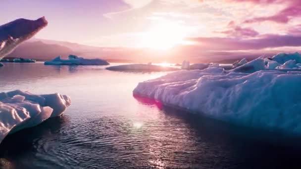 空中无人机飞越冰河上空冰湖中的粒子在落日落山的冰冠上漂浮冰岛探险 — 图库视频影像