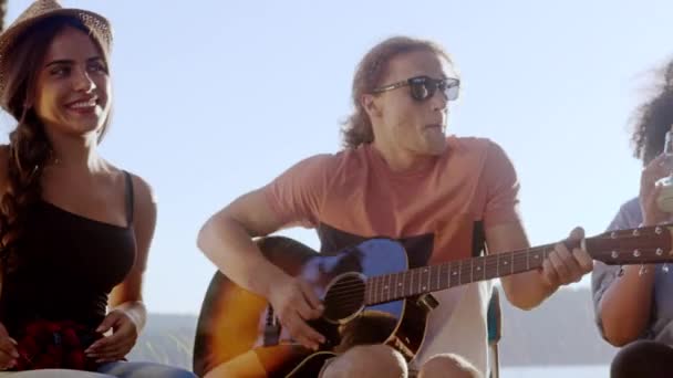 Diversi gruppi di giovani attraenti seduti intorno al falò nella foresta che cantano insieme alla chitarra mentre bevono e battono le mani Avventura musicale nel bosco Concetto musicale per il tempo libero Lento movimento girato su — Video Stock