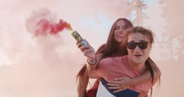 レイクショアでのピギーバックで幸せなカップルの男と女の回転と笑顔煙フレア関係の目標を保持しています幸せなエンゲージメントコンセプトスローモーションショットオンレッドエピックW 8k — ストック動画