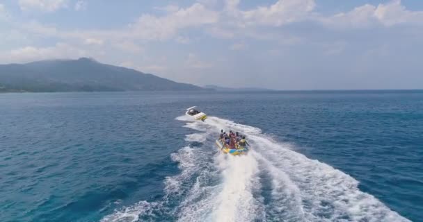 Vista aérea sobre os jovens equitação jet ski banana barco no oceano água azul clara no famoso feriado paraíso ilha paisagem marinha alta velocidade esportes radicais férias turismo aventura conceito quente verão — Vídeo de Stock