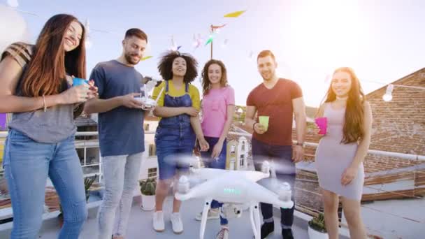 Diversos jóvenes del partido en la azotea que controlan el dron de Uav sonriendo emocionados jóvenes del partido Tiempo festivo Happy Technology Event Concept During Beautiful Urban Sunset Shot on Red Epic W 8K Slow — Vídeo de stock