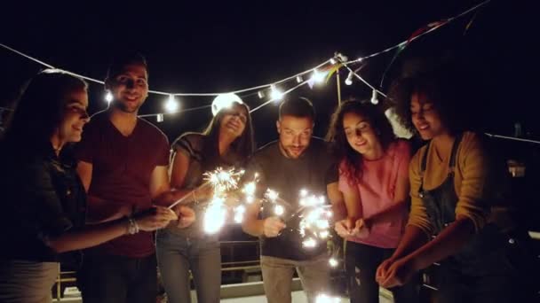 Divers jeunes gens de partie sur le toit joyeuse fête avec feu scintillant souriant à la caméra 4 juillet célébration anniversaire événement la nuit tourné sur Red Epic W 8K Slow Motion — Video