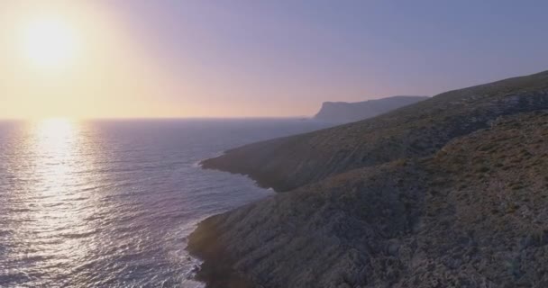 Droneskyting over havklipper og klart, blått vann, eksotisk gresk landskap, turismeparadis, på solnedgang, sommerdag – stockvideo