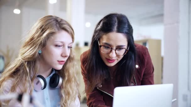 Dos jóvenes diseñadores de moda mirando a un ordenador portátil hablando entre sí Oficina feliz amistad cooperación cámara lenta 4K tiro en rojo épica 8K — Vídeos de Stock