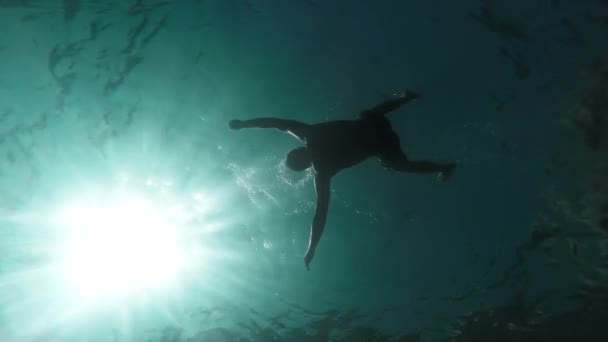 Silhouet man verdrinking zinken lichaam in diep water Slow Motion onderwater schot Oceaan moord gevaar verloren op zee verdrinken dood levenloos zwemmer zonnestralen golven rimpelingen sterfte concept GoPro HD — Stockvideo