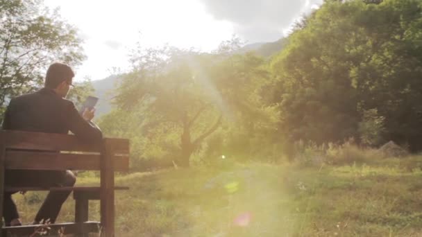 Muž oblek kapesní počítač Tablet lavice Sun příroda venkovní — Stock video