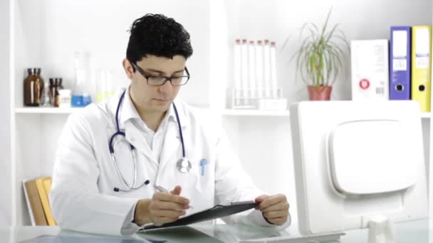Guapo joven médico masculino tomando notas diagnóstico de rayos X — Vídeos de Stock