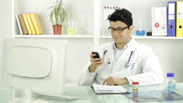 Όμορφος νέος γιατρός γραπτών μηνυμάτων χαμογελώντας κινητό τηλέφωνο — Αρχείο Βίντεο