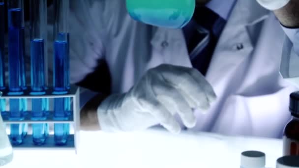 Chemiker mischt Flüssigkeitsmischkolben-Beobachtungsexperiment