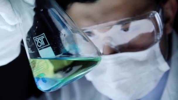 Крупним планом хімік, дивлячись на склянку хімічний експеримент — стокове відео