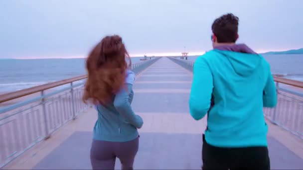Paar ochtend run strand Pier Sunrise recreatie gezonde levensstijl sport fit running man vrouw UHD — Stockvideo