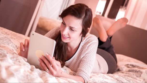 Tablet cama hermosa habitación mujer PC feliz sonrisa blanco ordenador acostado estilo de vida joven hogar Internet atractiva almohada tecnología casa — Vídeo de stock