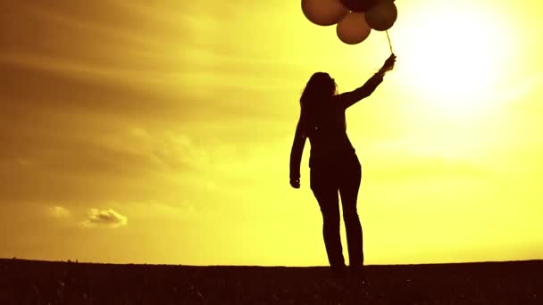Женщина с воздушными шарами ходит по лугу — стоковое видео