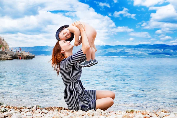 Junge schöne Mutter und ihr entzückender Sohn haben Spaß am Strand. — Stockfoto