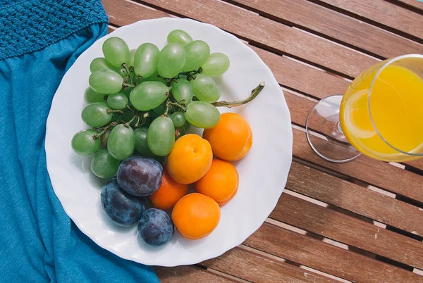 Pausa para almoço ou pequeno-almoço. Prato com frutas frescas misturadas na mesa de madeira com um copo de suco e roupas de verão . — Fotografia de Stock