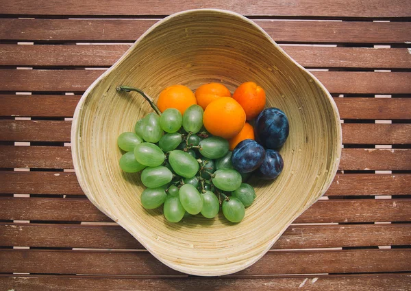 Prato com frutas frescas misturadas no fundo de madeira — Fotografia de Stock