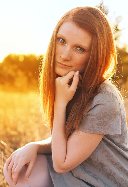 Schönheit junge Frau mit roten Haaren in goldenem Feld bei Sonnenuntergang. — Stockfoto