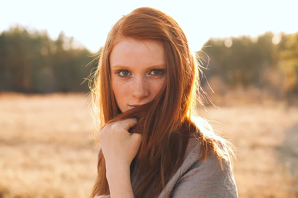 Belleza Mujer joven con el pelo rojo en el campo de oro al atardecer . — Foto de Stock