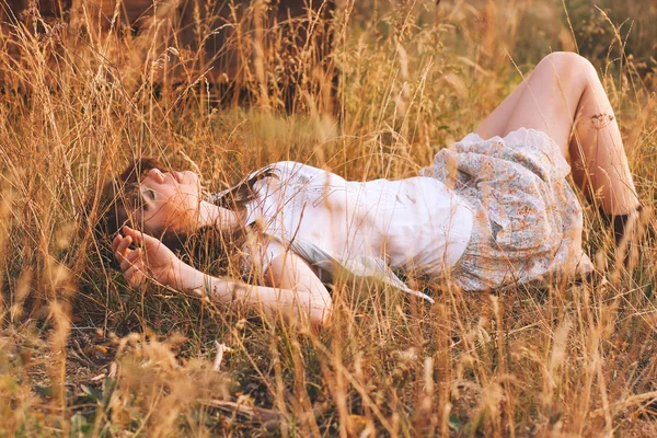 Belleza Mujer joven con cabello castaño en el campo de oro al atardecer . — Foto de Stock