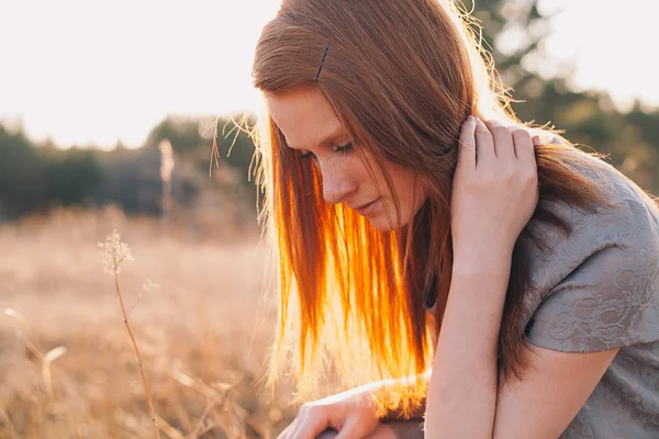 Belleza Mujer joven con el pelo rojo en el campo de oro al atardecer . — Foto de Stock