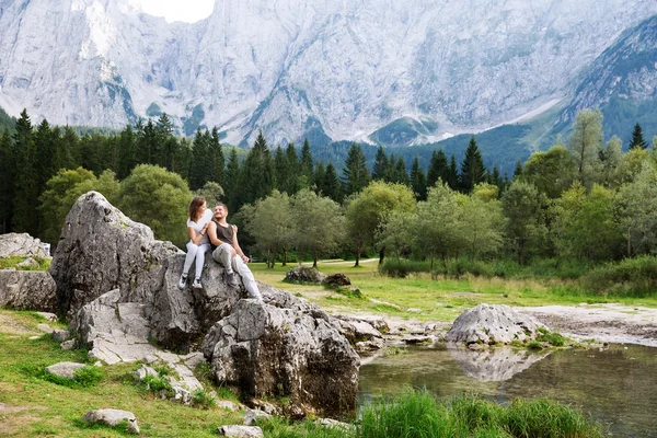 Pareja de viajeros en el Lago di Fusine con montañas de Mangart en el fondo . — Foto de Stock