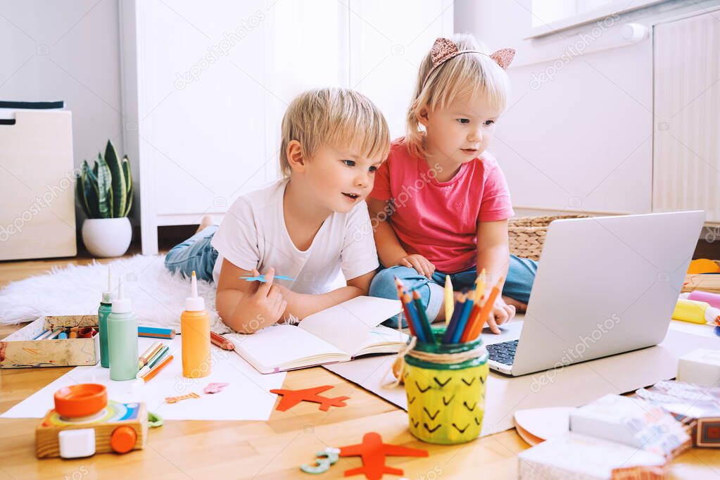 Kids using computer online technology to art creative, drawing or making crafts. Preschool children distance online education. Family leisure with little children at home or daycare.
