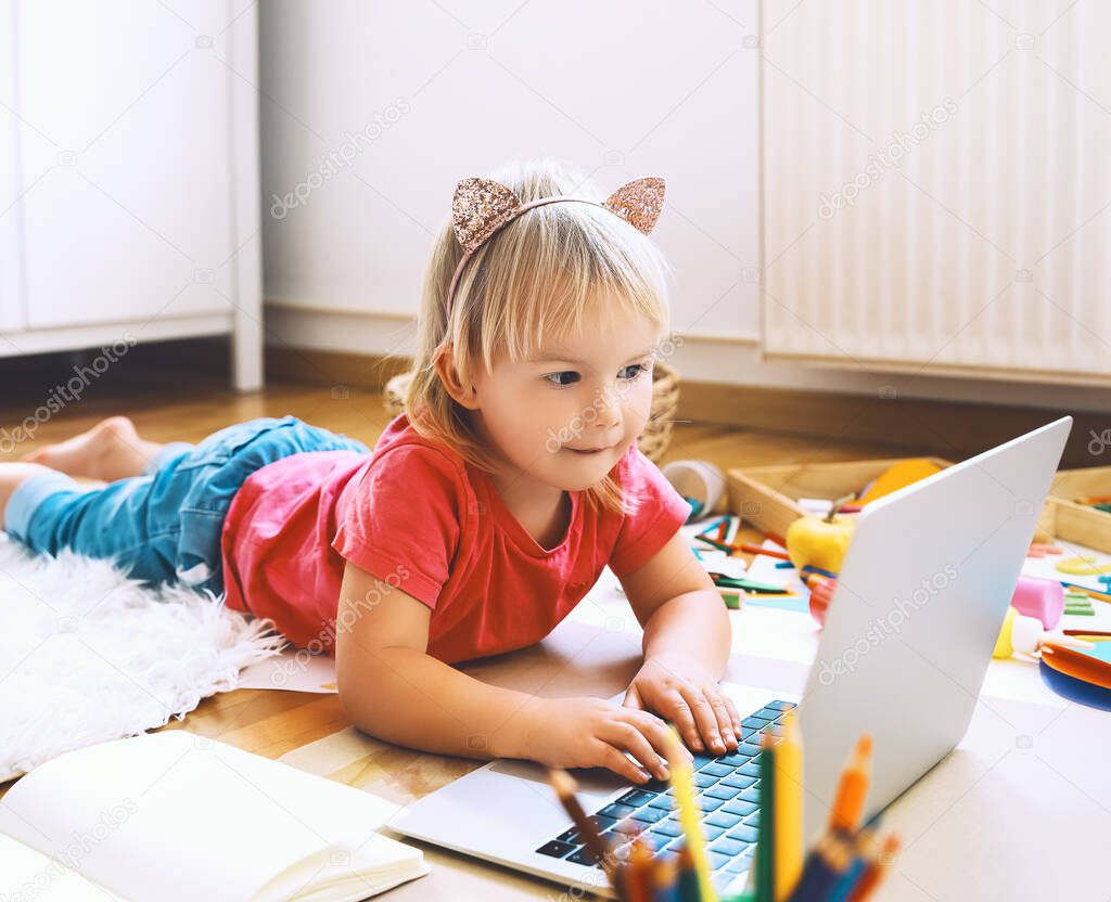 Little girl using computer online technology to art creative, drawing or making crafts. Preschool children distance online education. Family leisure with little kids at home or daycare.