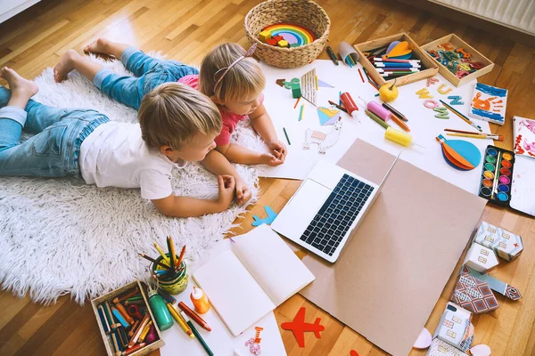 Kids drawing and making crafts with online art classes at home. Children using laptop to distance online education. Background for preschool, kindergarten or family daycare. Childcare and technology.