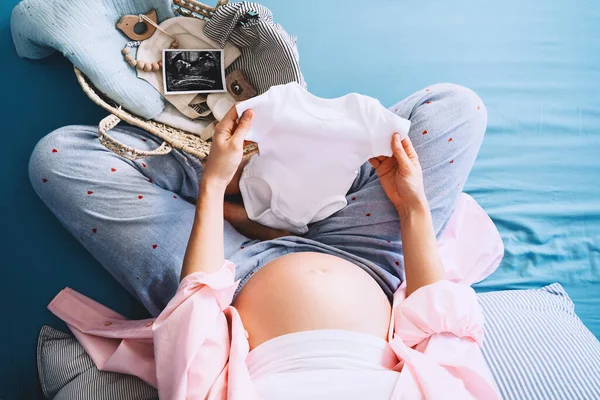 Hamile Bir Kadın Elinde Bebek Tulumu Hamilelik Sırasında Doğuma Hazırlanıyor — Stok fotoğraf