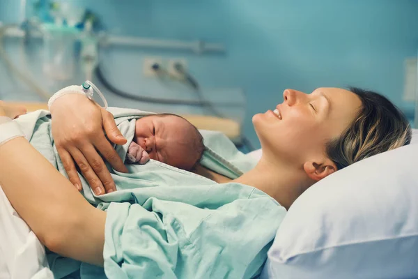 Anne ve yeni doğan. Doğum hastanesinde doğum. Genç anne doğumdan sonra bebeğine sarılıyor. Doğum yapan kadın. Doğumdan sonra bebek hayatının ilk anları.