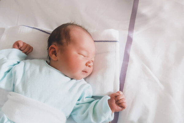 Новорожденный мирно спит в больничной палате после родов. Первые дни жизни ребенка после рождения.