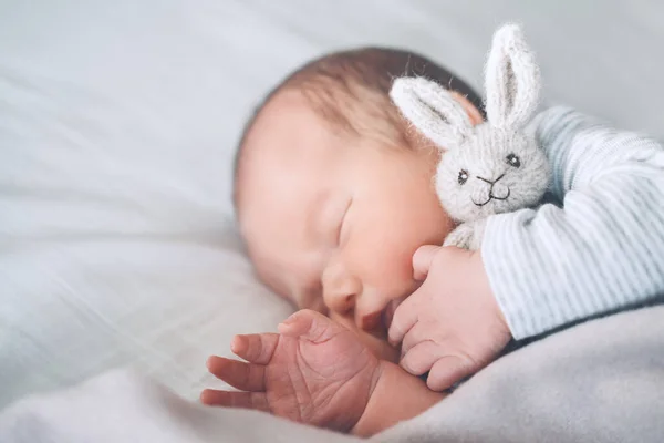 新生儿在出生的头几天睡觉 一个星期大的男婴的画像 他睡得很安详 带着一个可爱的软玩具躺在布底的婴儿床里 — 图库照片