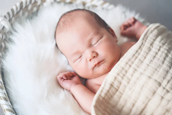 用白色毛皮衬里的毯子包裹在篮子里睡觉的新生儿 一个星期大的新生儿的肖像 — 图库照片