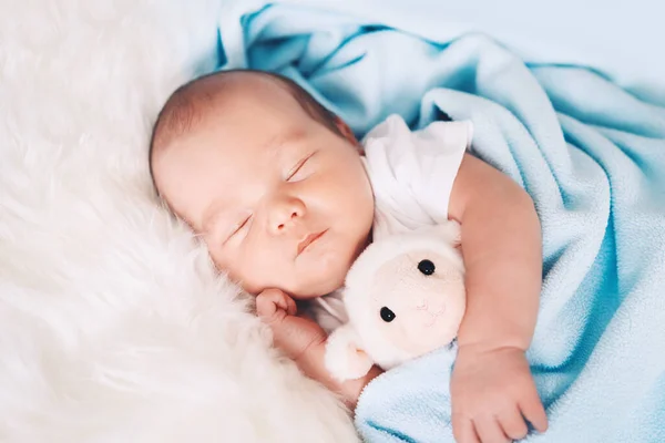 新生儿在出生的头几天睡觉 一个星期大的男婴的画像 他睡得很安详 带着一个可爱的软玩具躺在布底的婴儿床里 — 图库照片