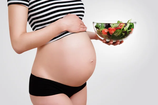 Femme enceinte avec un bol de légumes — Photo