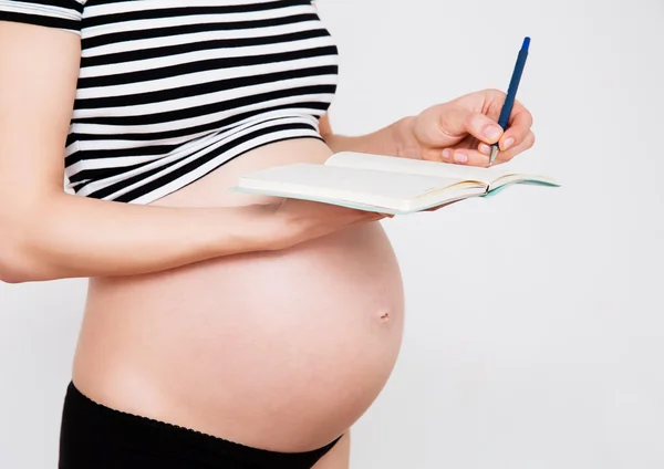 Donna incinta fa la lista di controllo Fotografia Stock