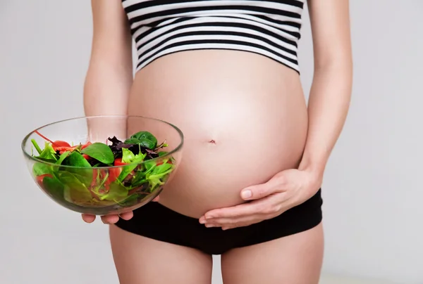 Donna incinta con una ciotola di verdure Foto Stock