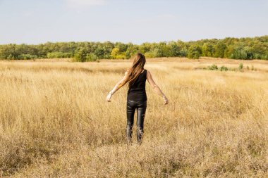 Siyah elbiseli güzel, genç, siyah saçlı kadın tarlada duruyor..