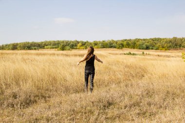 Siyah elbiseli güzel, genç, siyah saçlı kadın tarlada duruyor..