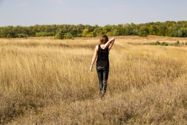 Siyah elbiseli güzel, genç, siyah saçlı kadın tarlada duruyor..