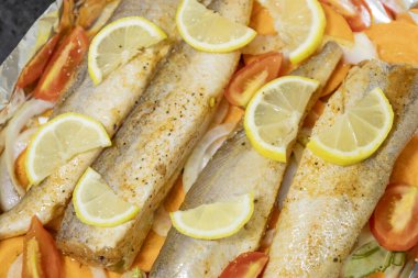 Fırında limonlu, domatesli, havuçlu ve soğanlı fırında pişmiş çiğ hake. Öğlen ya da akşam yemeği için lezzetli balık, diyet için mükemmel. Sebzeli pişirmek için lezzetli ve taze balık..