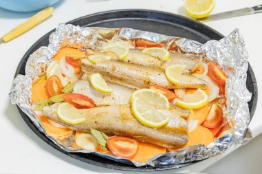 Fırında limonlu, domatesli, havuçlu ve soğanlı fırında pişmiş çiğ hake. Öğlen ya da akşam yemeği için lezzetli balık, diyet için mükemmel. Sebzeli pişirmek için lezzetli ve taze balık..