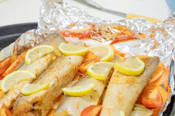 Fırında limonlu, domatesli, havuçlu ve soğanlı fırında pişmiş çiğ hake. Öğlen ya da akşam yemeği için lezzetli balık, diyet için mükemmel. Sebzeli pişirmek için lezzetli ve taze balık..