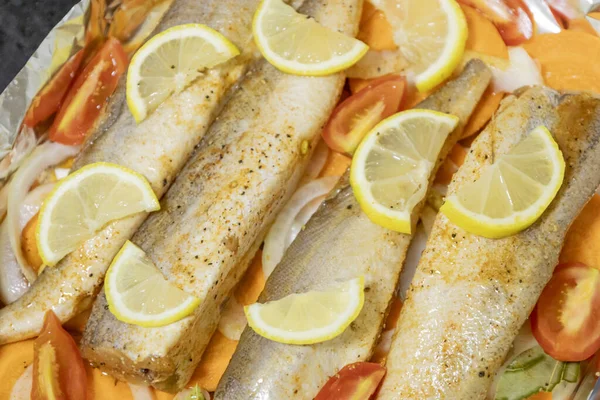 Fırında limonlu, domatesli, havuçlu ve soğanlı fırında pişmiş çiğ hake. Öğlen ya da akşam yemeği için lezzetli balık, diyet için mükemmel. Sebzeli pişirmek için lezzetli ve taze balık..