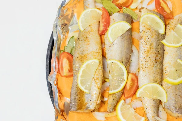 Fırında limonlu, domatesli, havuçlu ve soğanlı fırında pişmiş çiğ hake. Öğlen ya da akşam yemeği için lezzetli balık, diyet için mükemmel. Sebzeli pişirmek için lezzetli ve taze balık..